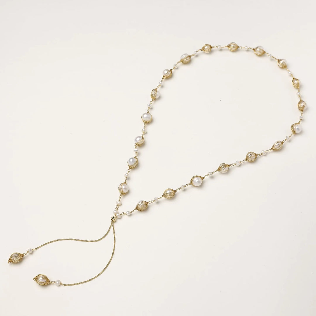 Adjustable gold lariat necklace with freshwater pearls nested in delicate cage settings and Y-shaped tassel drop
