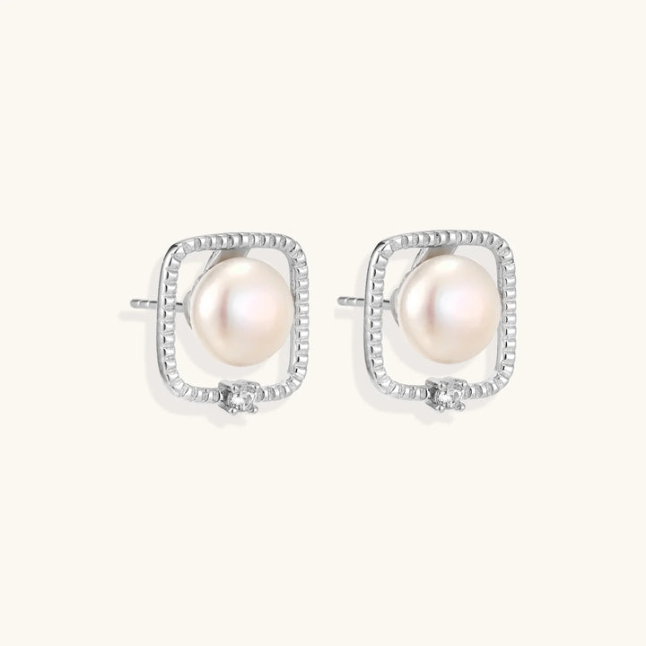 Rhodium-plated silver stud earrings with cushion frame, centered freshwater pearl, and tiny crystal accent