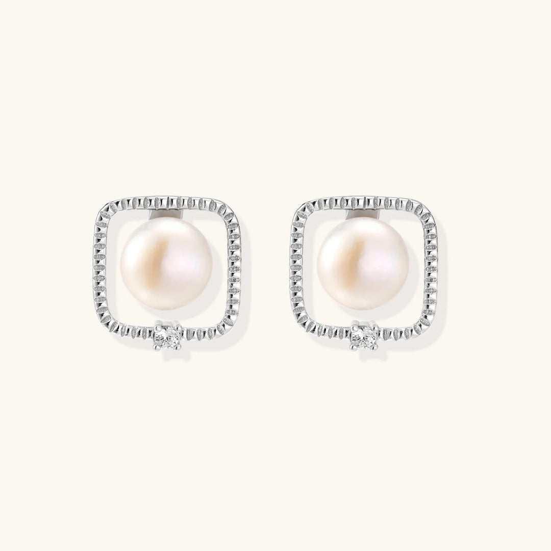 Rhodium-plated silver stud earrings with cushion frame, centered freshwater pearl, and tiny crystal accent