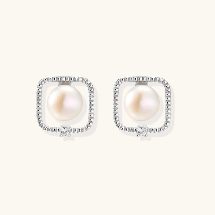 Rhodium-plated silver stud earrings with cushion frame, centered freshwater pearl, and tiny crystal accent