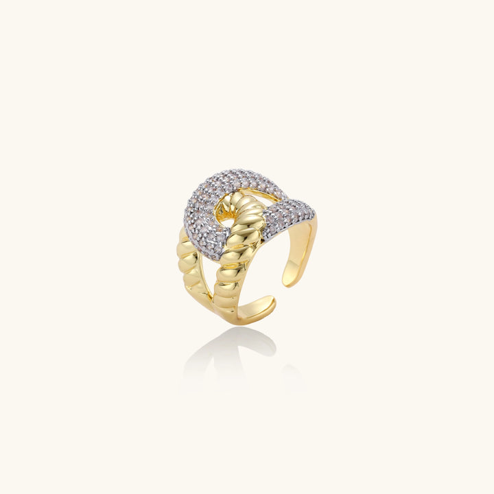 Chunky gold-plated chain-link ring with curved segments and sparkling zirconia crystals on neutral background