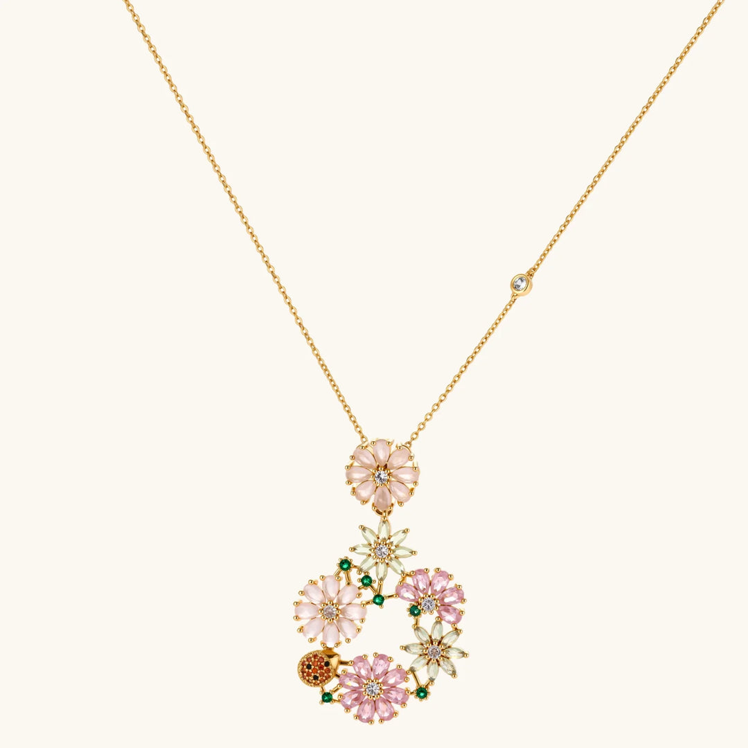 14K gold plated jewelry set with pink and green cubic zirconia flowers arranged in wreath design on cream background