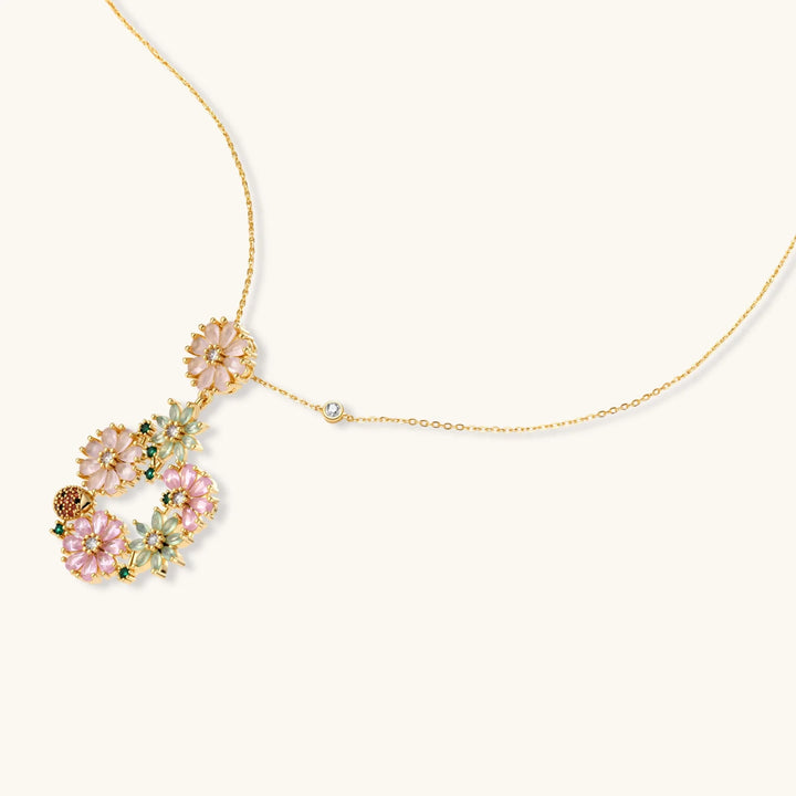 14K gold plated jewelry set with pink and green cubic zirconia flowers arranged in wreath design on cream background