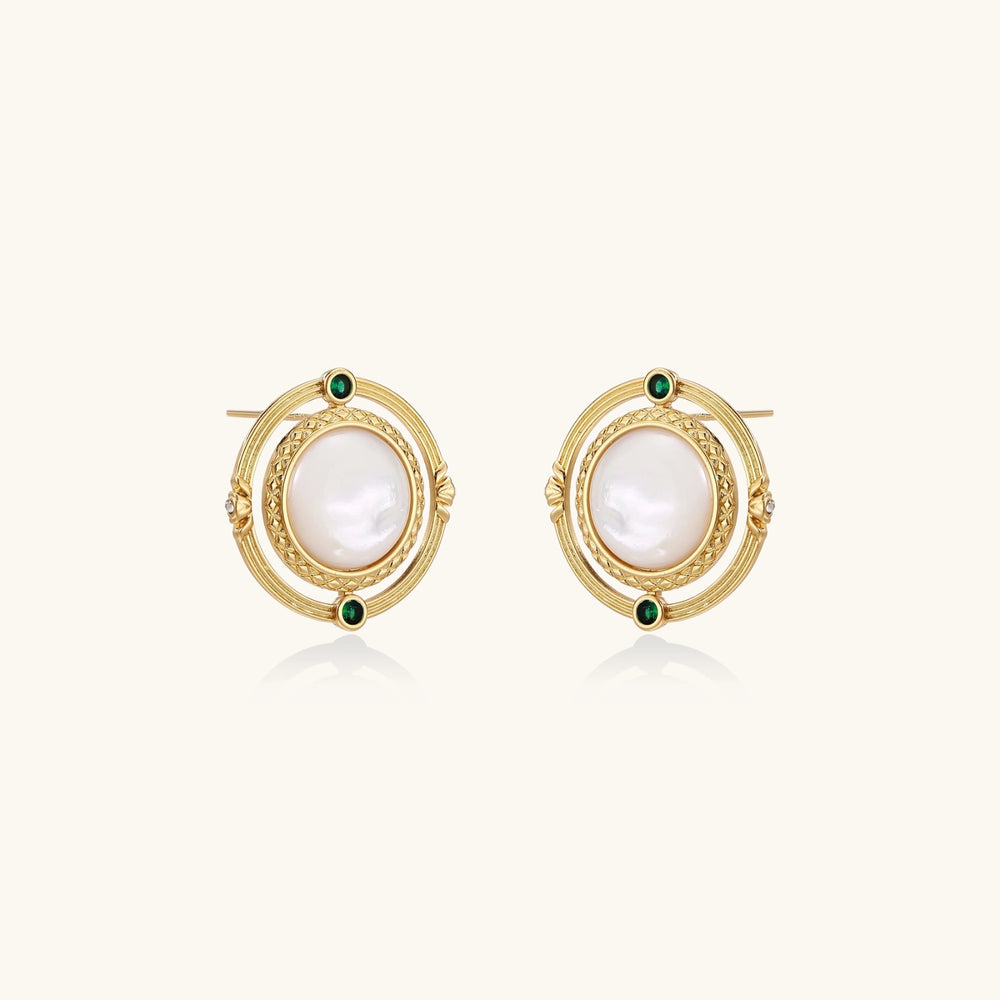 Circular gold stud earrings with iridescent mother-of-pearl center and green zirconia accents on cream background.
