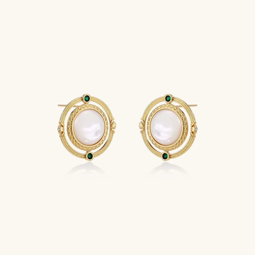 Circular gold stud earrings with iridescent mother-of-pearl center and green zirconia accents on cream background.